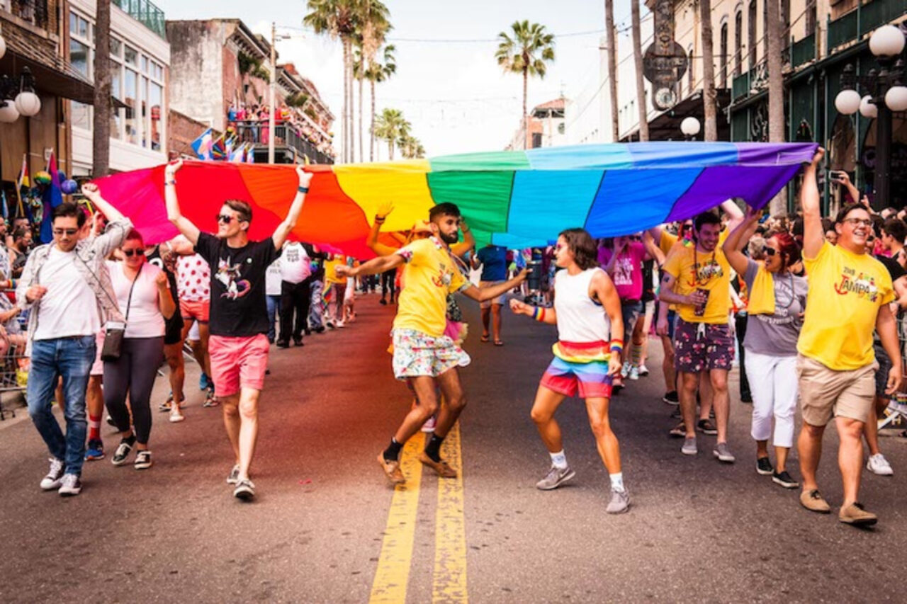 People walking down the street with the Pride flag held above them near our Tampa hotel