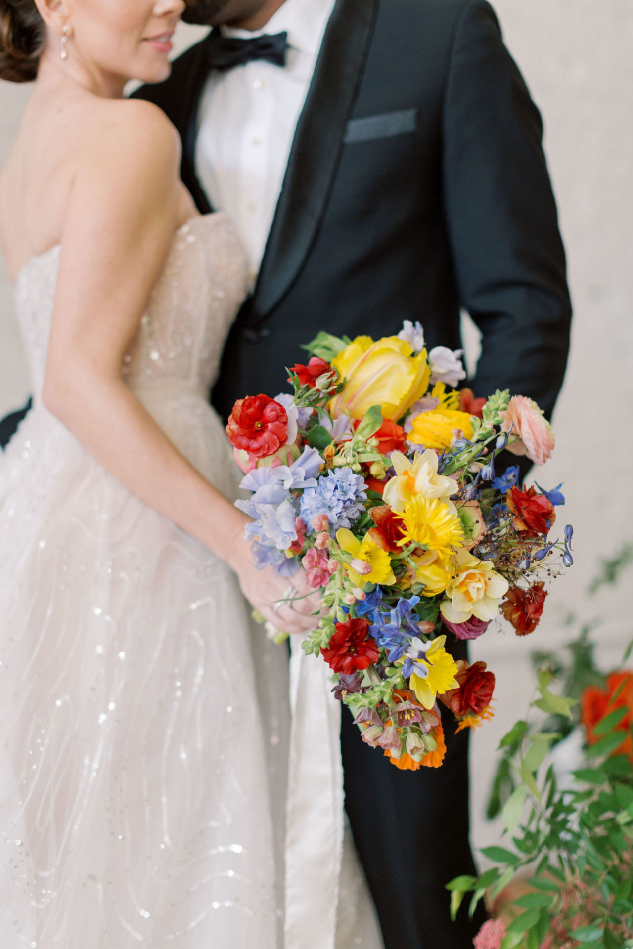 Wedding couple in white & black holding a vibrant bouquet of yellow, red and blues in Tampa, FL
