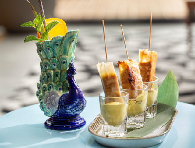 Cuban sticks in shot glasses and a cocktail in a peacock-shaped glass