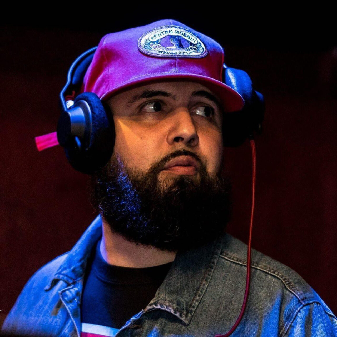 Music in Flor Fina by DJ Wally Rios with his headphones, red baseball cap and beard.